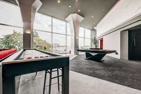 A billiard table is in the middle of a room with a view of the city.